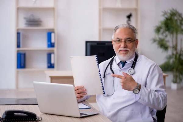 Klinikte çalışan yaşlı erkek doktor. — Stok fotoğraf