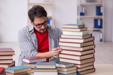 Genç bir erkek öğrenci ve sınıfta çok fazla kitap var.