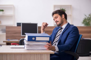 Genç bir erkek çalışan ve ofiste çok fazla iş var.