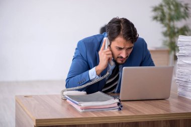 Ofisteki aşırı işten memnun olmayan genç bir erkek işçi.