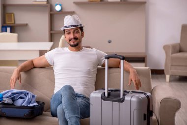 Young man preparing for trip at home clipart