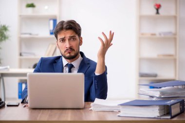 Ofisteki aşırı işten memnun olmayan genç bir erkek işçi.