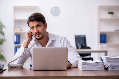 Genç bir erkek çalışan ve ofiste çok fazla iş var.