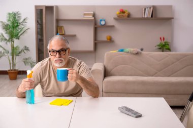 Yaşlı adam evde ev işi yapıyor.