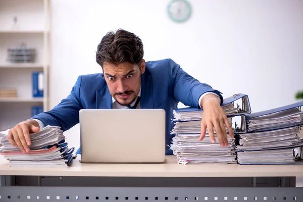 Genç bir erkek çalışan ve ofiste çok fazla iş var.