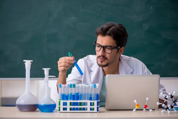 Young male chemist in front of blackboard — Stock Photo, Image