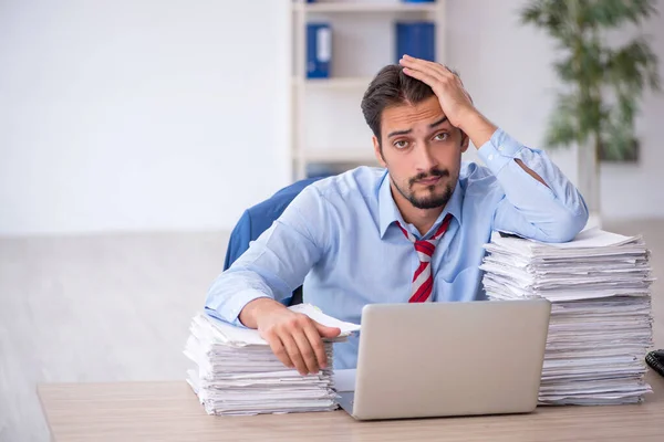 Ung manlig anställd och för mycket arbete på kontoret — Stockfoto