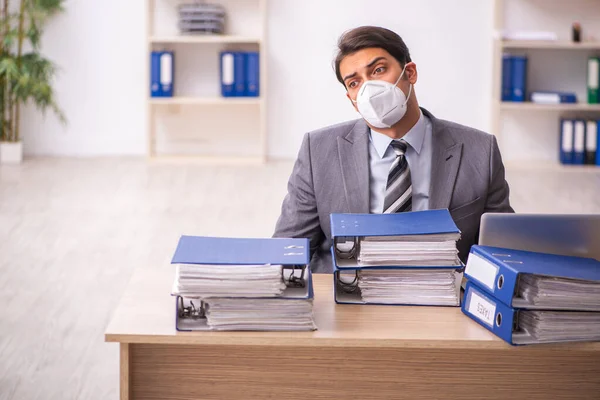 Ung manlig anställd som arbetar på arbetsplatsen under en pandemi — Stockfoto