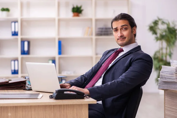 Joven empleado masculino infeliz con el trabajo excesivo — Foto de Stock