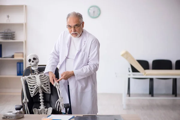 Viejo doctor con esqueleto en la clínica —  Fotos de Stock