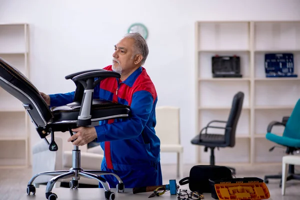 Viejo reparador masculino reparando silla de oficina — Foto de Stock