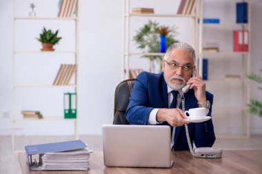 Eski erkek çalışanımız teneffüste kahve içiyor.