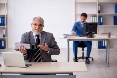 Yaşlı erkek patron ve ofiste çalışan genç erkek çalışan.