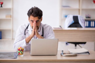 Klinikte çalışan genç erkek doktor.