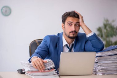 Genç bir erkek çalışan ve ofiste çok fazla iş var.