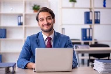 Genç bir erkek çalışan ve ofiste çok fazla iş var.