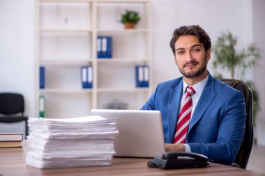 Genç bir erkek çalışan ve ofiste çok fazla iş var.