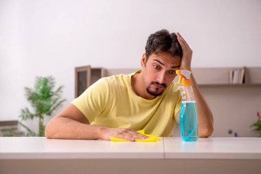 Genç adam evde ev işi yapıyor.