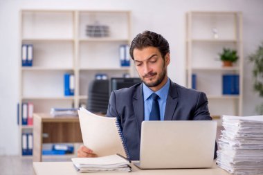 Genç bir erkek çalışan ve ofiste çok fazla iş var.