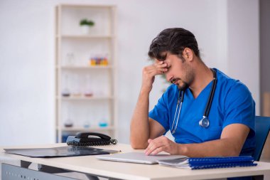 Klinikte çalışan genç erkek doktor.