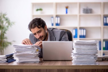 Genç bir erkek çalışan ve ofiste çok fazla iş var.