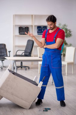 Genç erkek marangoz atölyede çalışıyor.