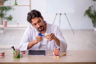 Klinikte çalışan genç erkek dişçi.