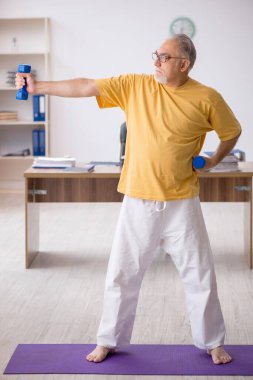 Ofiste spor egzersizleri yapan eski bir işadamı.