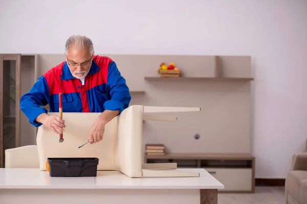 Vieux charpentier masculin réparer chaise à l'intérieur — Photo