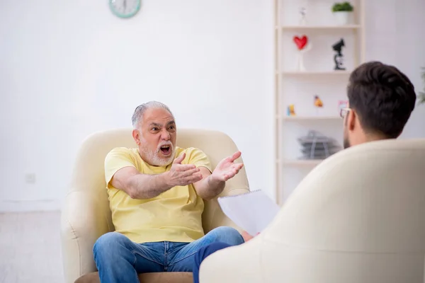 Vieil homme visitant un jeune psychothérapeute masculin — Photo