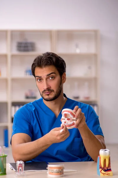 Jonge mannelijke tandarts werkzaam in de kliniek — Stockfoto