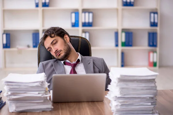 Ung manlig anställd och för mycket arbete på kontoret — Stockfoto