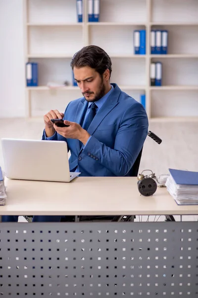 Ung manlig anställd i rullstol sitter på kontoret — Stockfoto