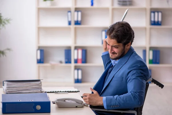 Ung manlig anställd i rullstol sitter på kontoret — Stockfoto