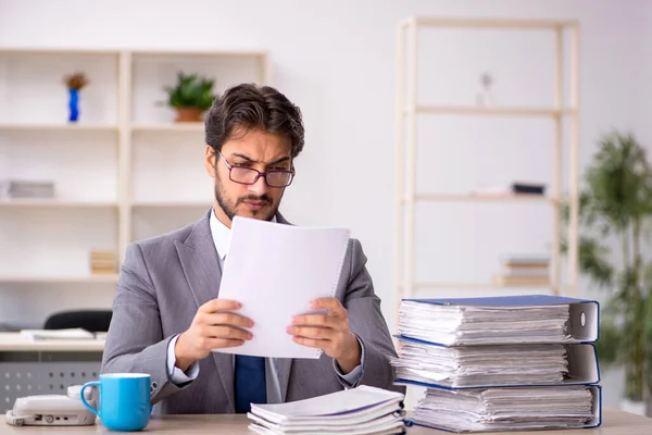 Ung manlig anställd och för mycket arbete på kontoret — Stockfoto