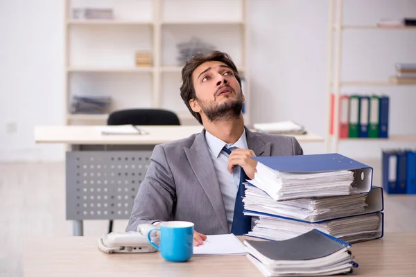 Joven empleado masculino y demasiado trabajo en la oficina — Foto de Stock