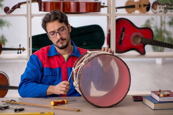 Mladý muž opravuje hudební nástroje v dílně — Stock fotografie
