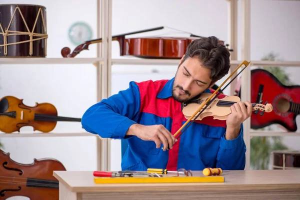 Jongeman repareert muziekinstrumenten in werkplaats — Stockfoto