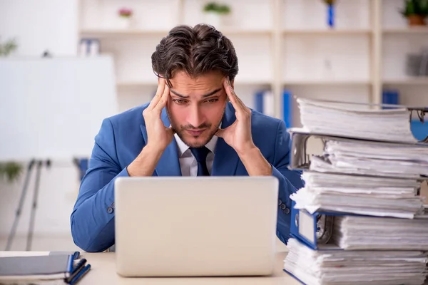 Joven empleado masculino y demasiado trabajo en la oficina — Foto de Stock