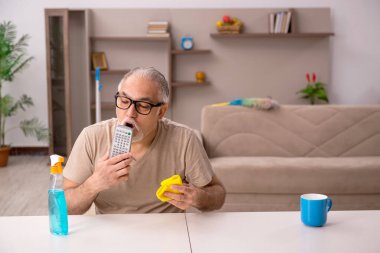 Yaşlı adam evde ev işi yapıyor.