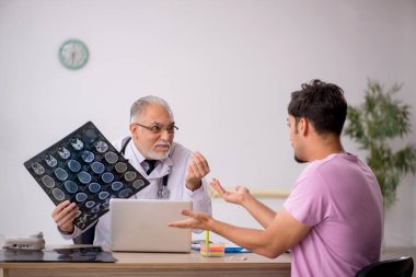Genç erkek hasta yaşlı erkek doktor radyolojisti ziyaret ediyor.