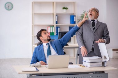 Yaşlı erkek patron ve ofiste çalışan genç erkek çalışan.