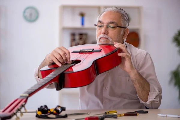 Alter Mann repariert Musikinstrumente in Werkstatt — Stockfoto