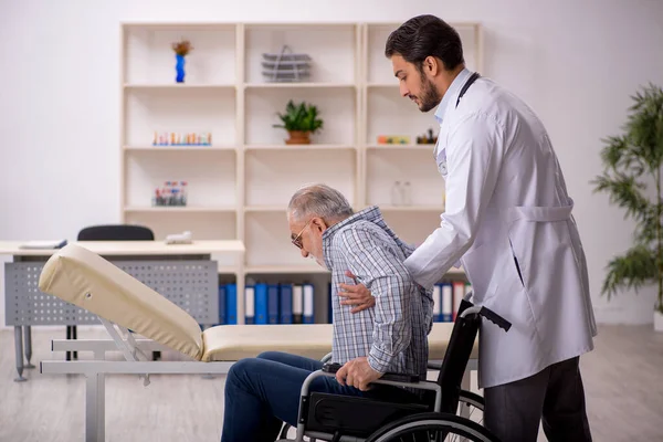 Oude man in rolstoel op bezoek bij jonge mannelijke arts — Stockfoto