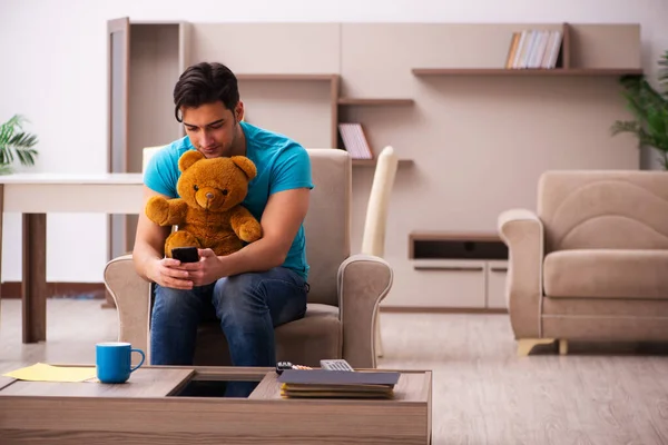 Jeune homme assis avec jouet ours à la maison — Photo