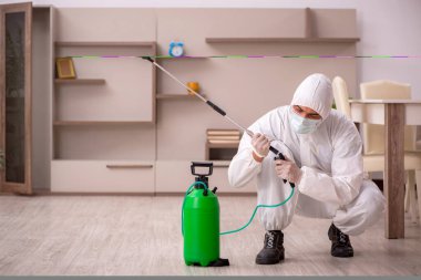 Genç erkek müteahhit evde haşere kontrolü yapıyor.