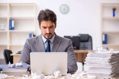 Genç bir erkek çalışan ve ofiste çok fazla iş var.