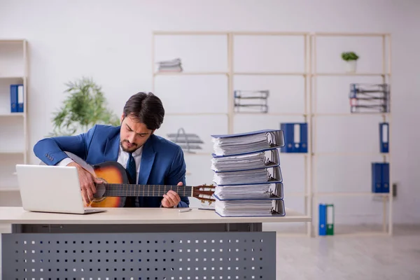 Jeune employé masculin jouant de la guitare sur le lieu de travail — Photo