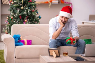 Genç adam Noel 'i evde yalnız kutluyor.