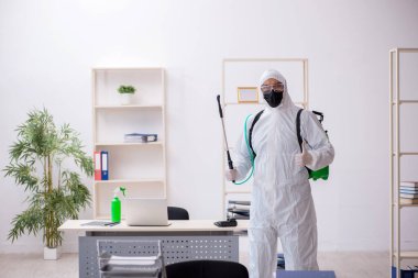 Young male contractor disinfecting office during pandemic